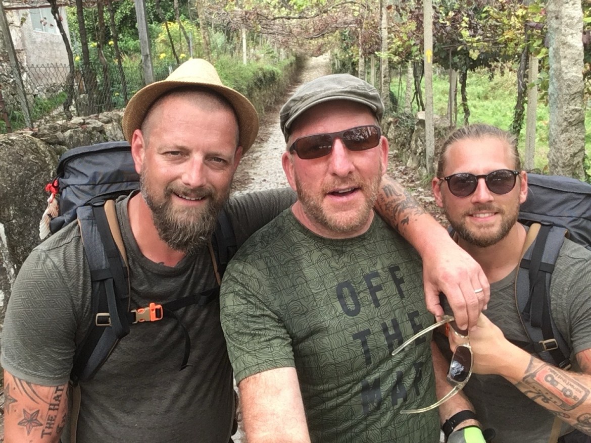 Three pilgrims with backpacks taking a selfie on the trail