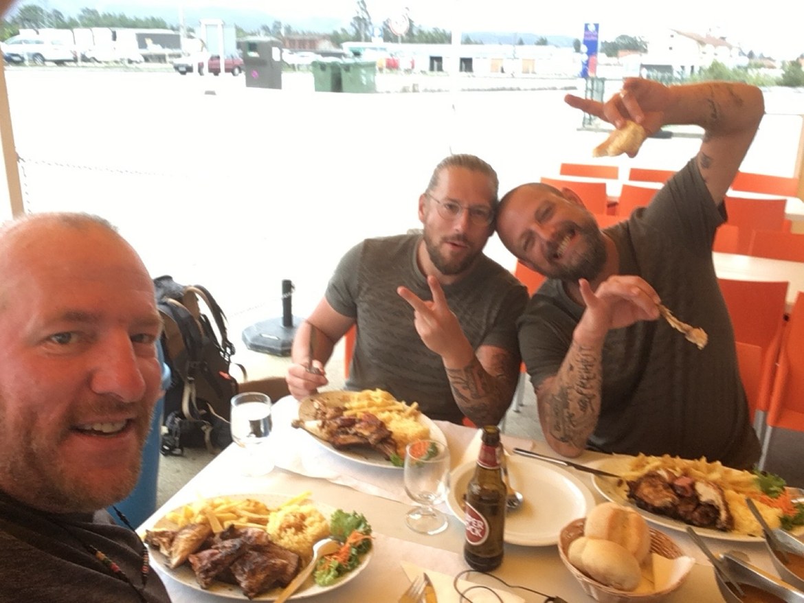 Three pilgrims at a restaurant table with roast chicken
