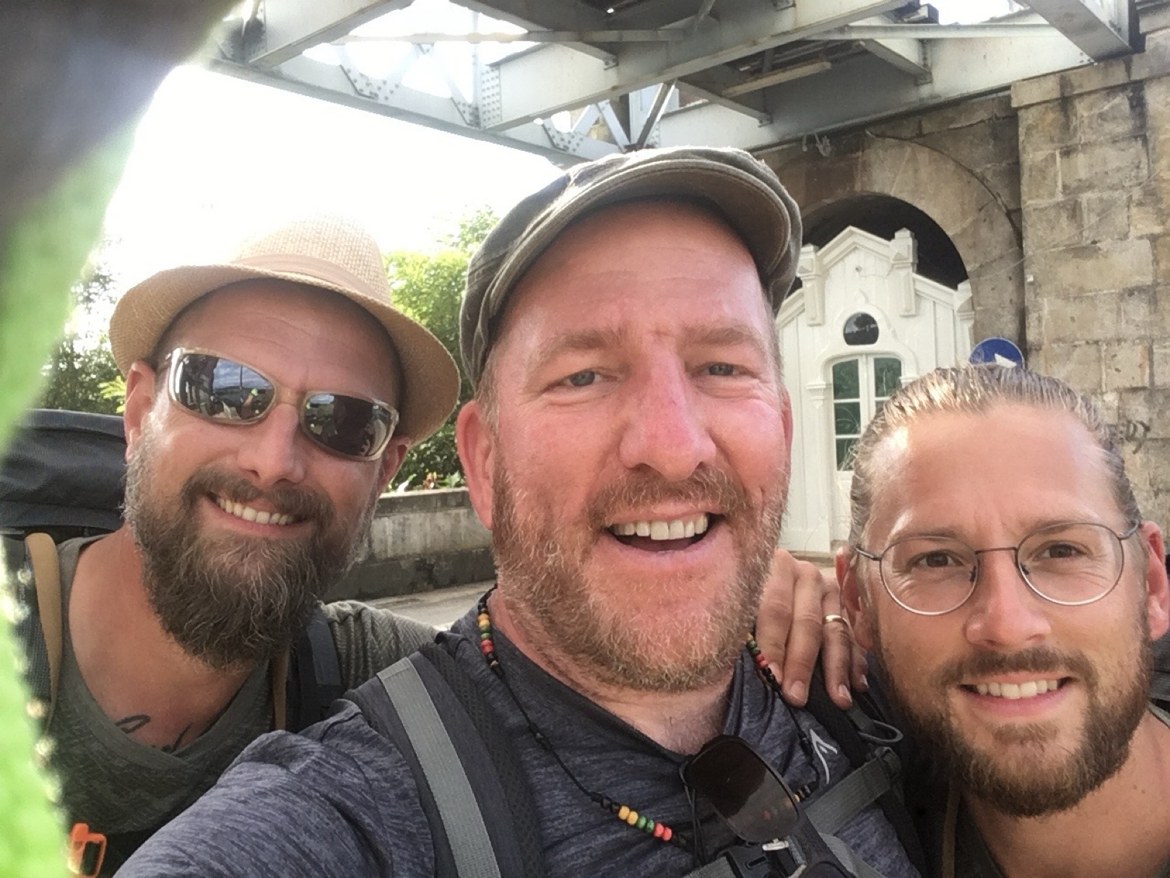 Three pilgrims taking a selfie beneath the bridge into Spain