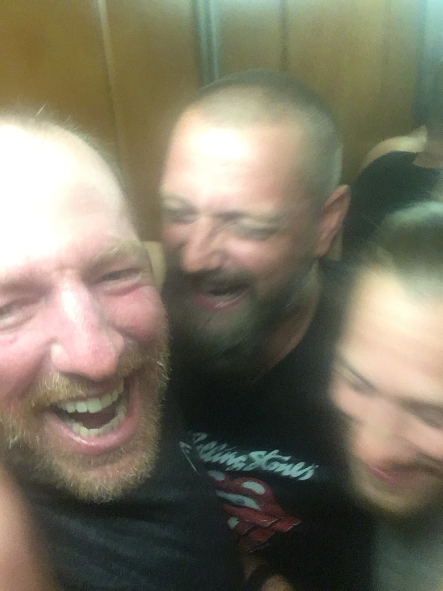 Three pilgrims laughing in a blurry elevator selfie