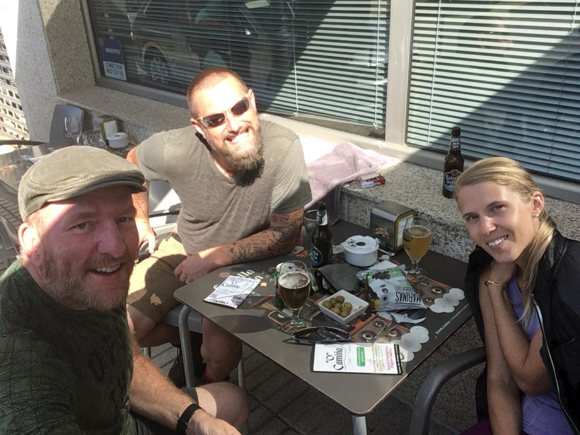 Three pilgrims with beers and olives at a sunny café terrace