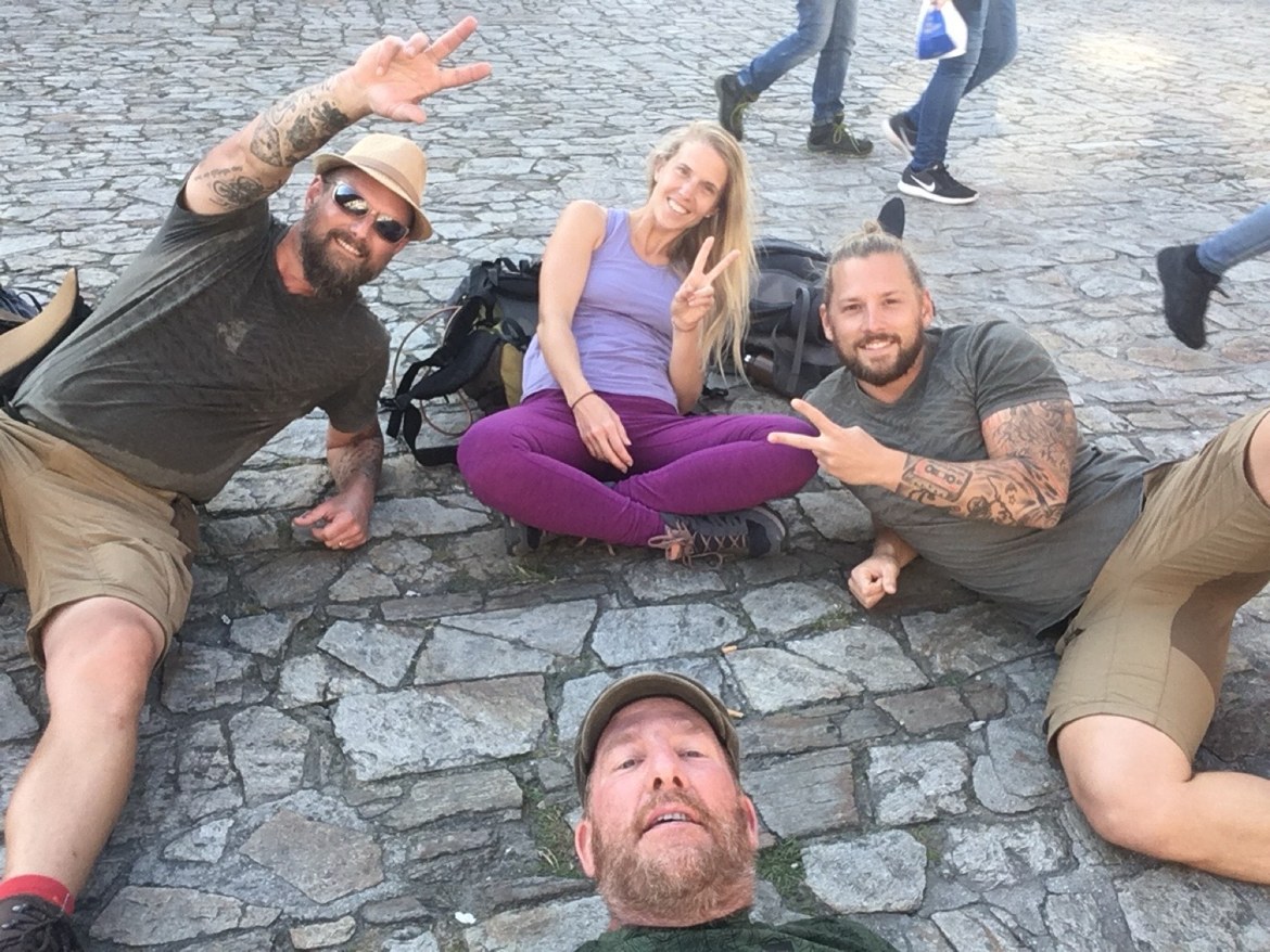 Four pilgrims reclining on the cobblestones of the Obradoiro square in Santiago