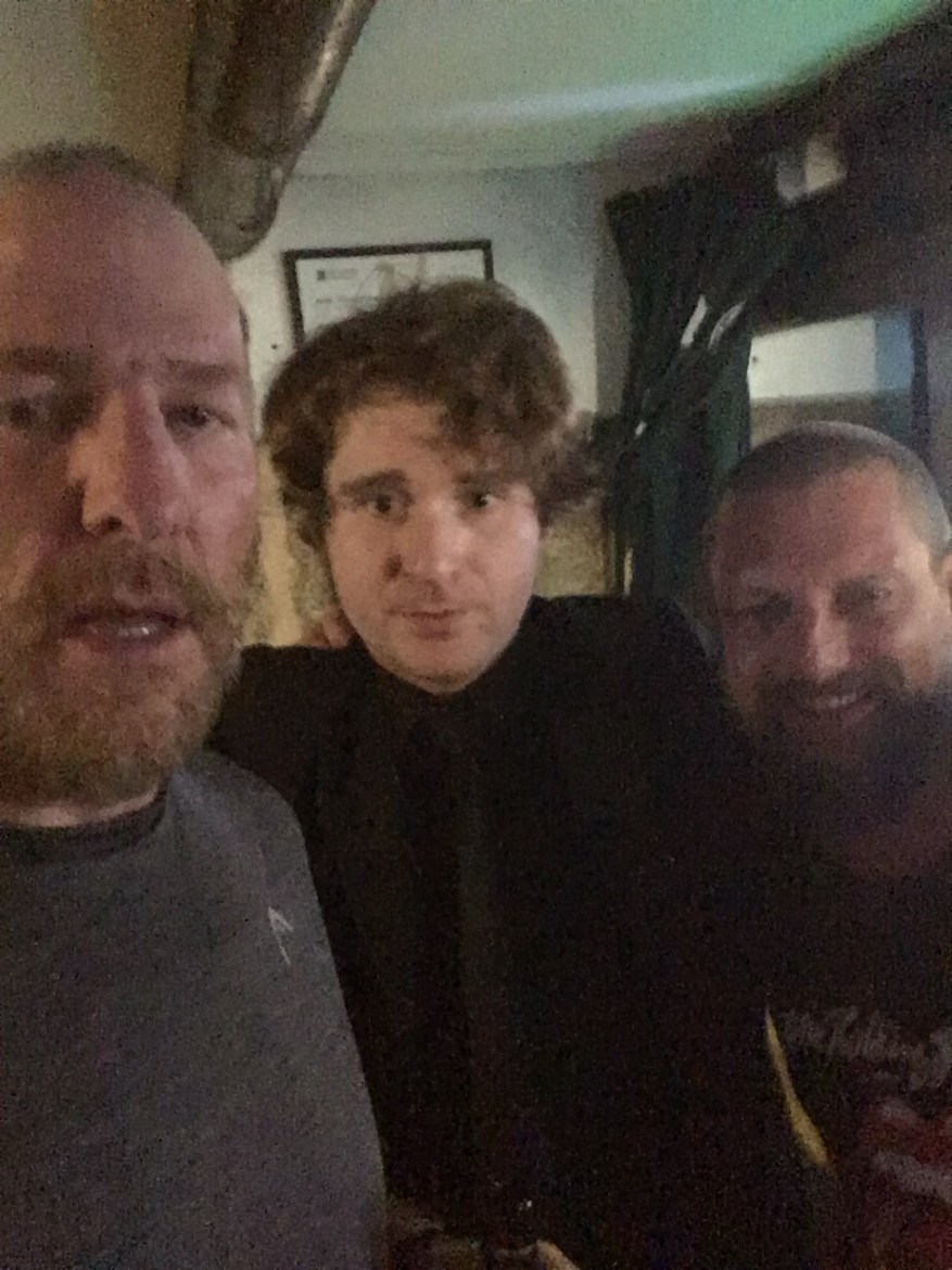 Three pilgrims smiling in a Santiago bar on the last night