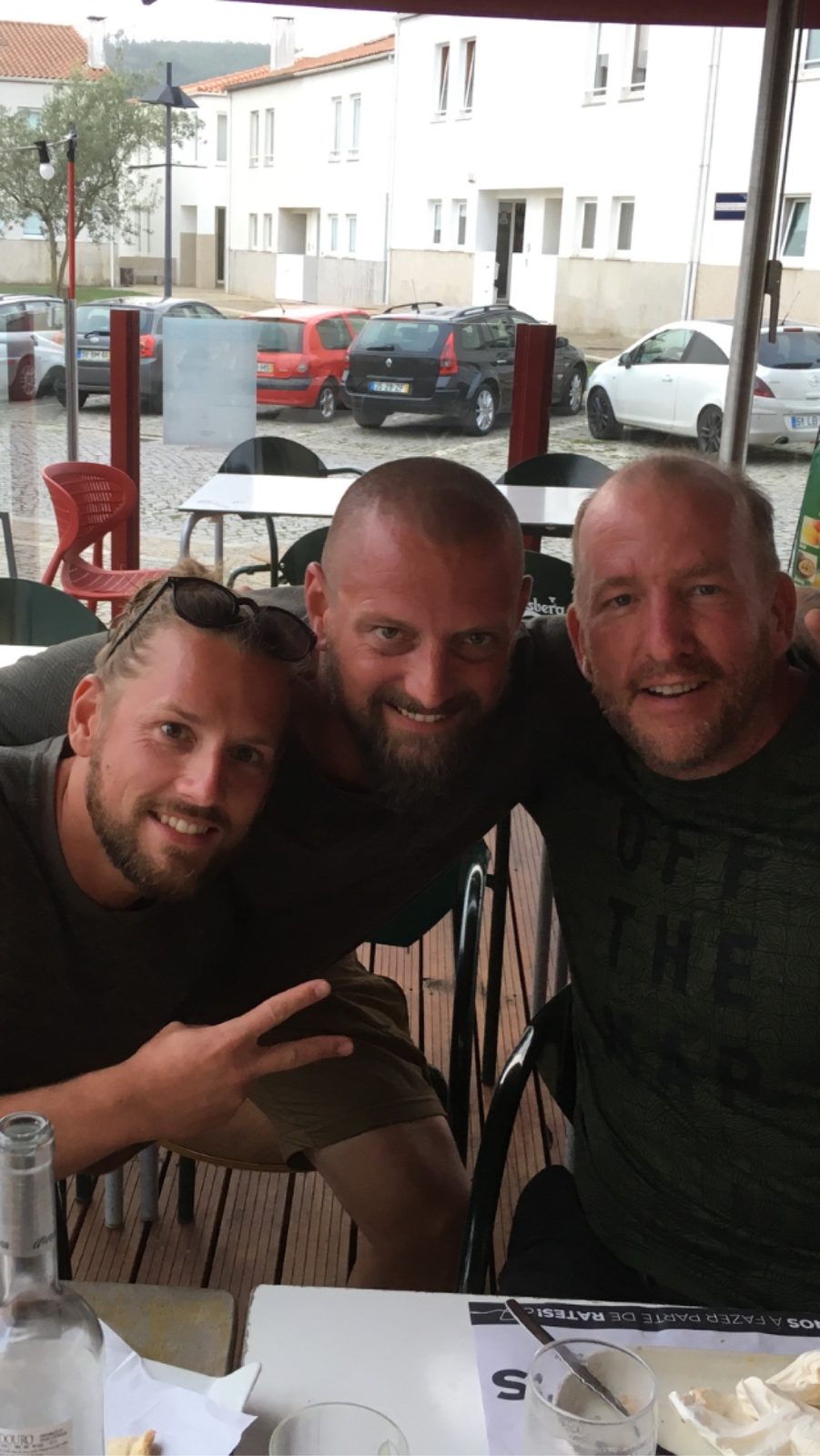 The three Camino Brothers - Mike, Nicki and Dennis - smiling together at an outdoor café in Portugal