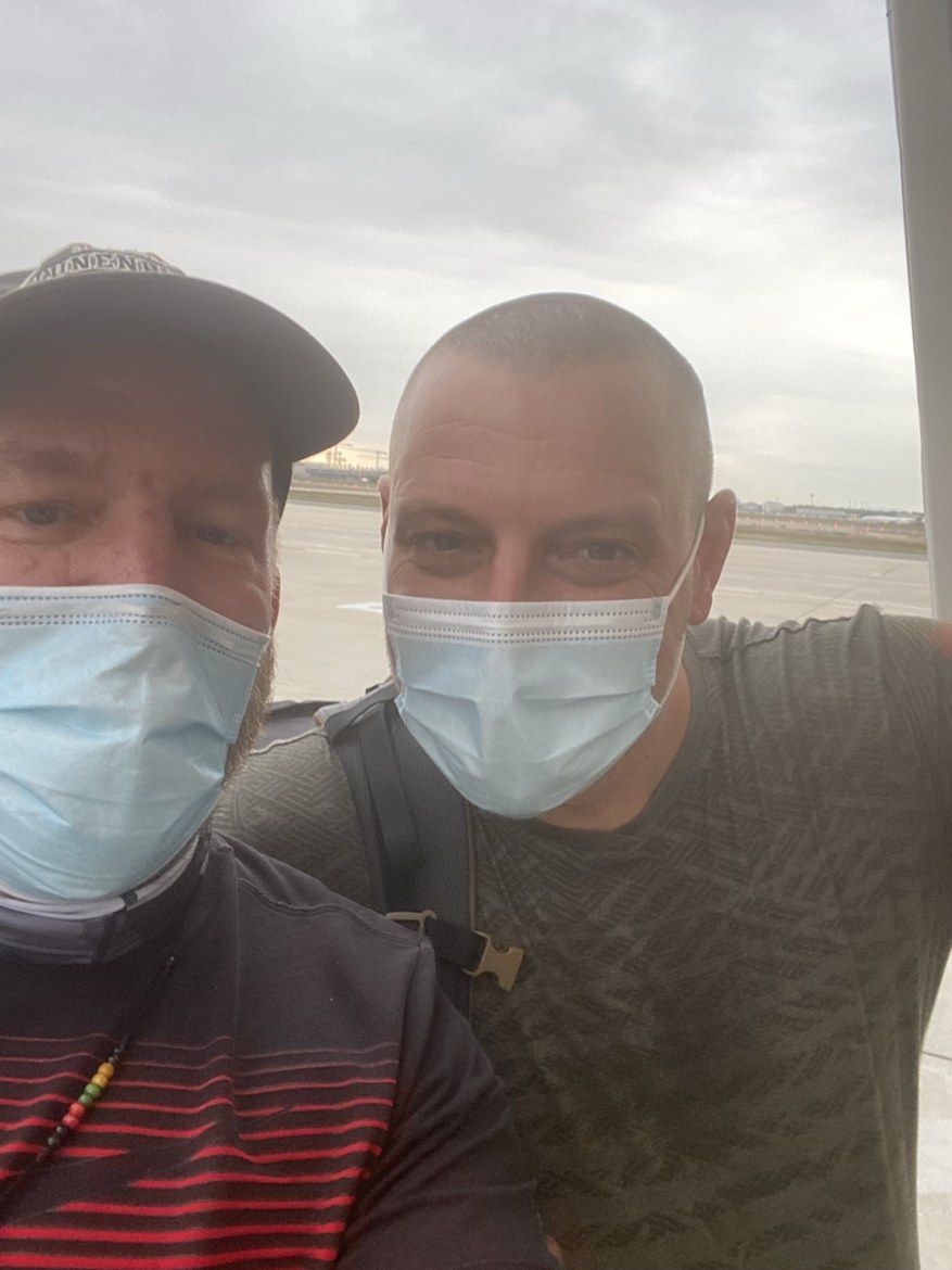 Two pilgrims in face masks taking a selfie at the airport