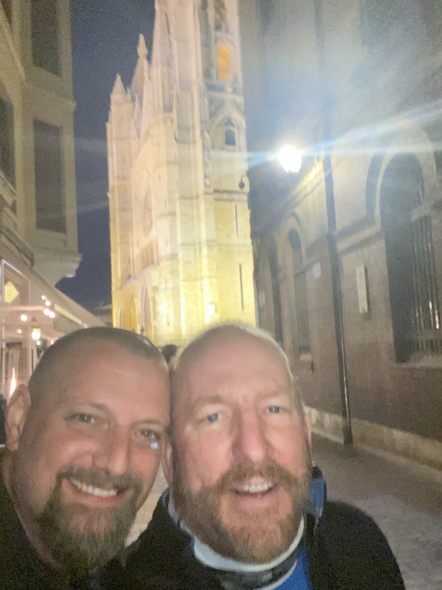 A pilgrim taking a selfie before León cathedral lit up at night