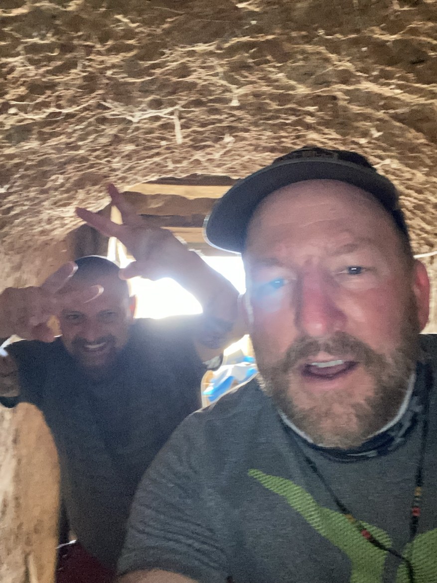 Two pilgrims taking a selfie beneath a stone overhang on the trail
