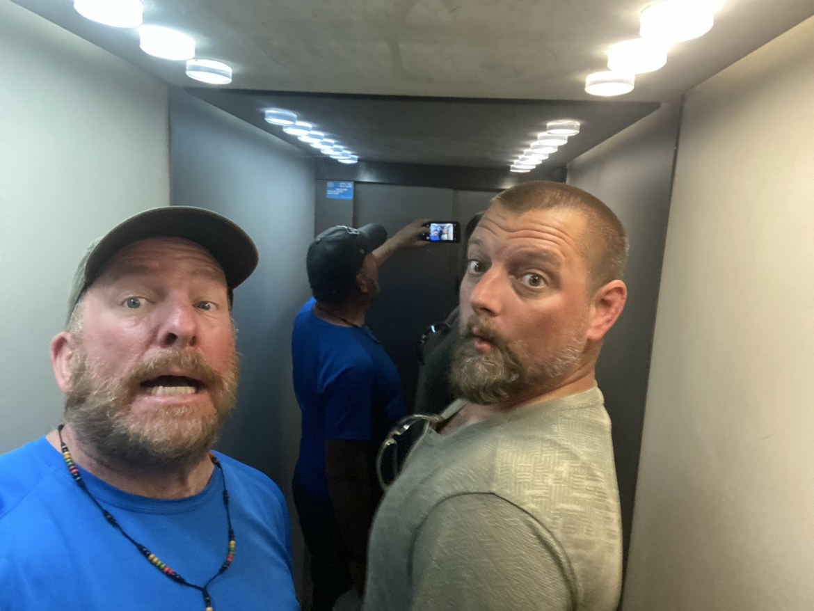 Two pilgrims pulling faces in a mirrored elevator