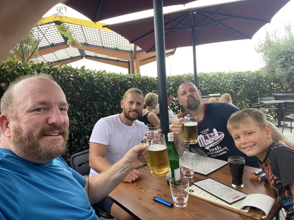 Mike, Dennis, family and friends raising glasses at an outdoor beer-garden table