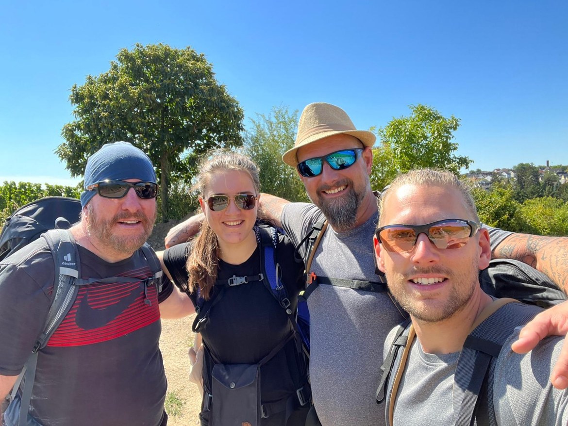 Four hikers - Mike, a friend, Nicki in a straw hat and Dennis - taking a selfie on the trail