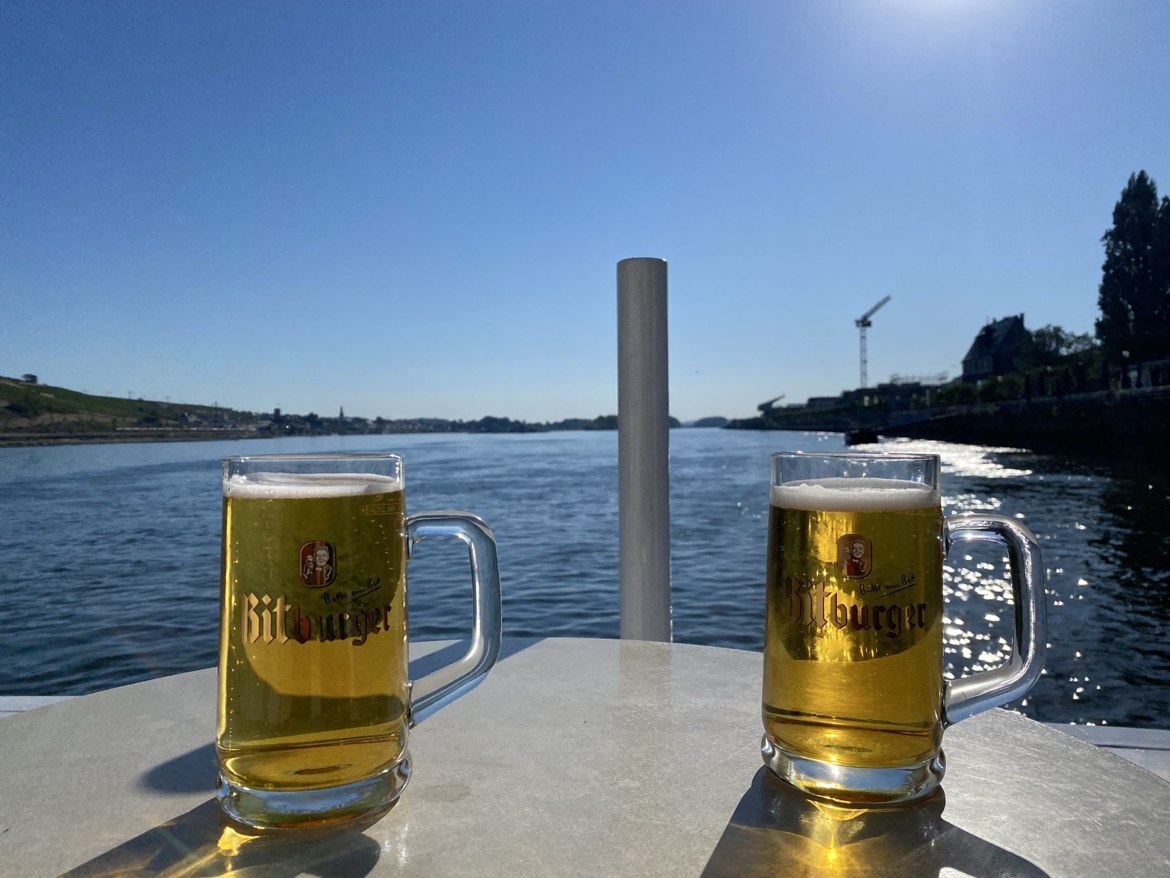 Two Bitburger beer mugs on a table overlooking the Rhine