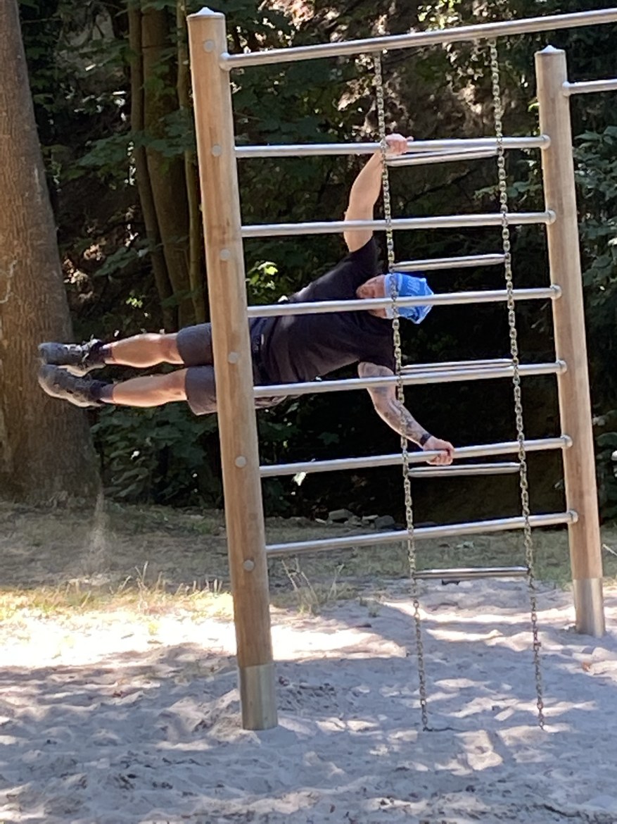 Dennis holding a human flag on playground bars in the woods