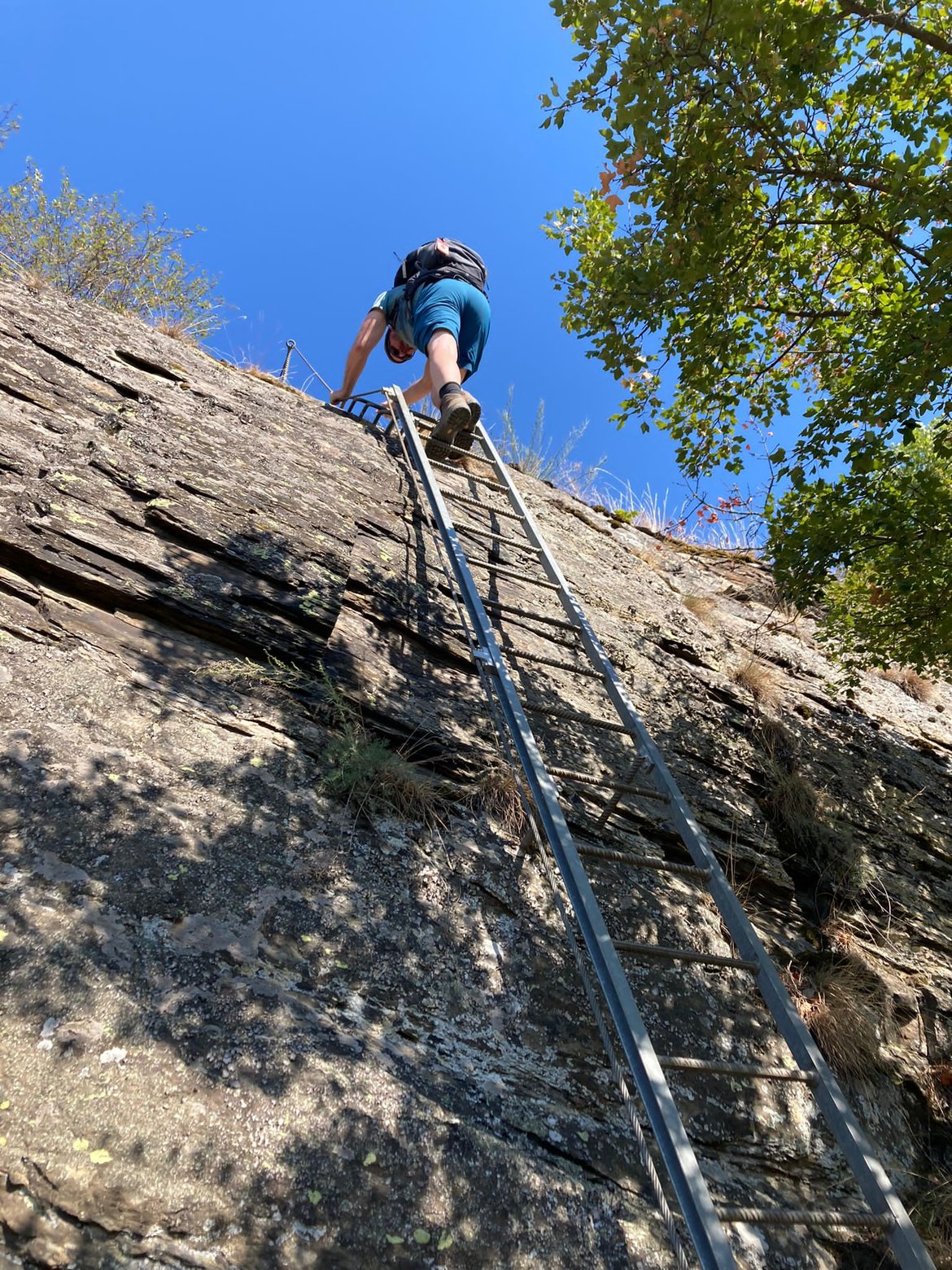 Climbing a steel ladder bolted to the slate rock face, seen from below