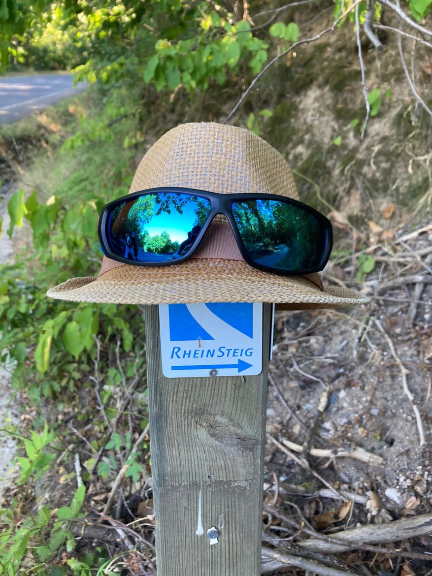 A straw hat and sunglasses resting on a Rheinsteig waymark post