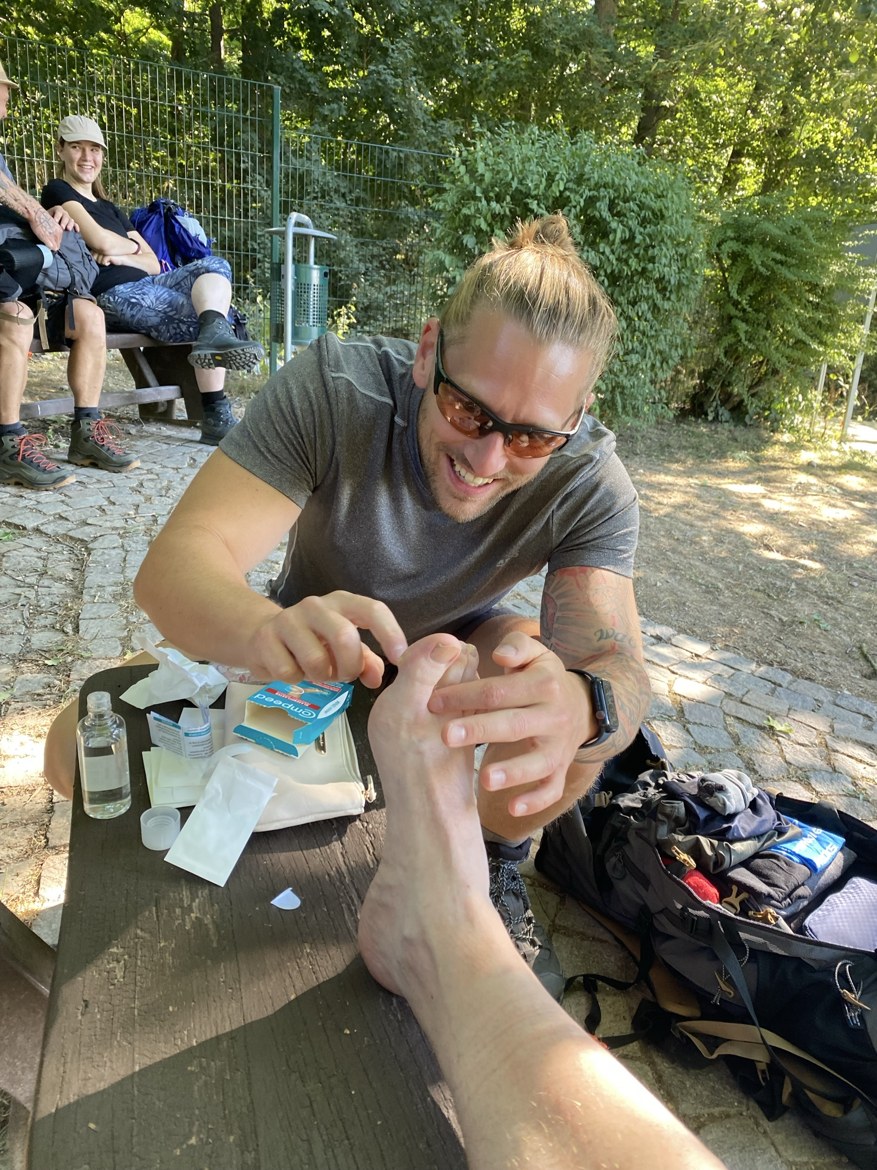 Dennis fixing a blister on Mike's foot with a Compeed plaster at a rest stop