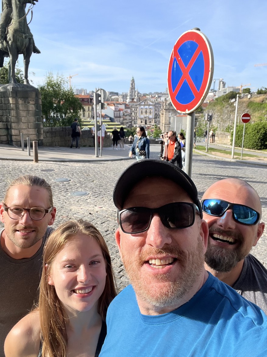 Mike and Sarah smiling in a Porto square at dusk, a statue behind them