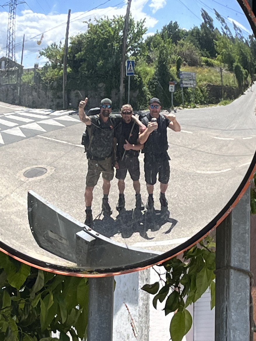 The three brothers reflected in a convex traffic mirror on a country road