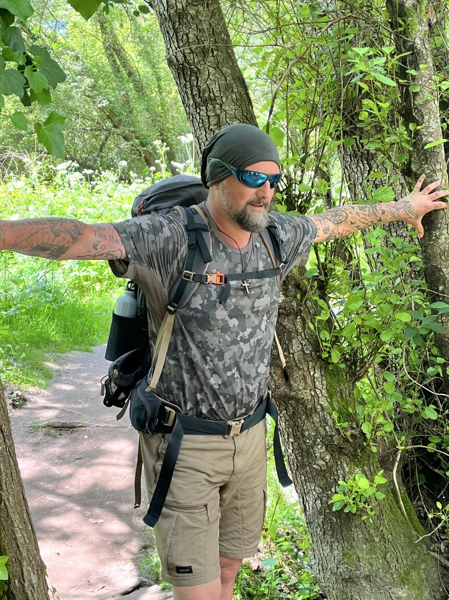 Nicki standing among trees with his arms spread wide