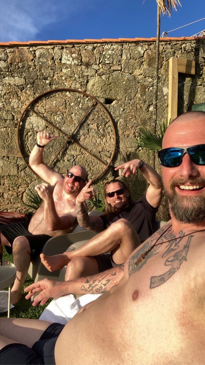 The three brothers resting against a stone wall in the sun
