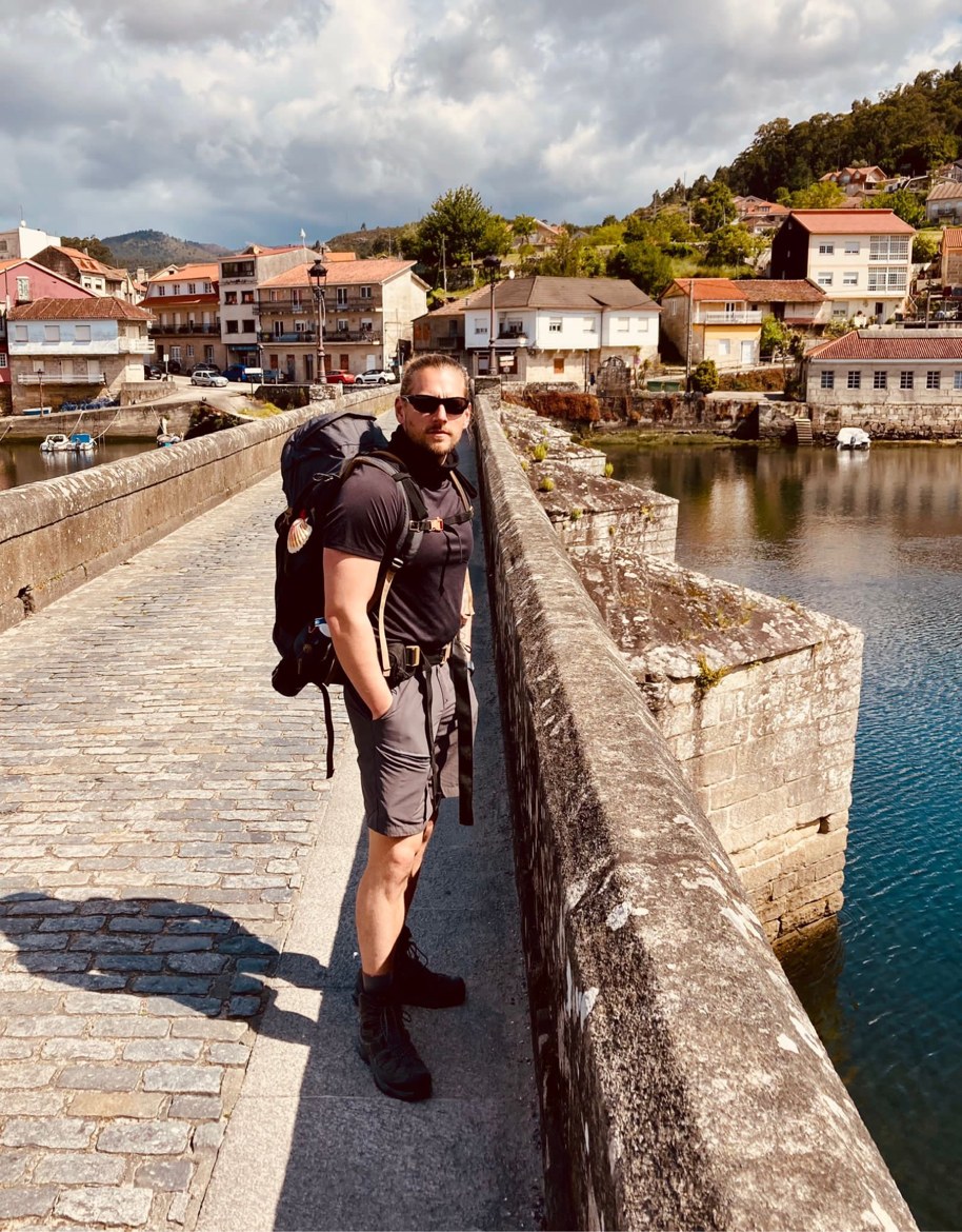 Dennis standing on the old stone bridge at Ponte Sampaio, the village behind him