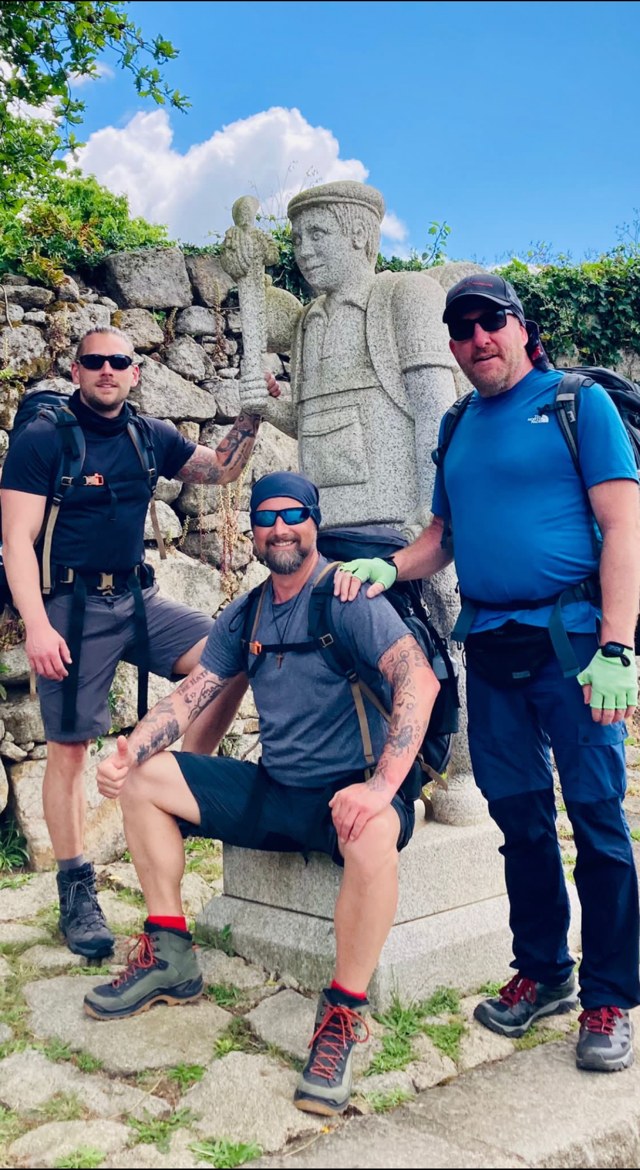The three brothers posing with a tall stone pilgrim statue