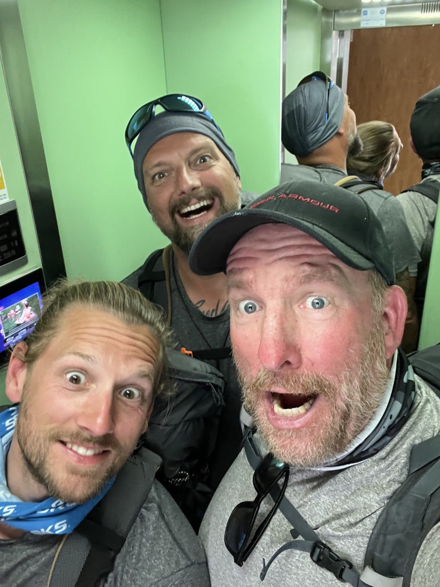 The three brothers pulling faces in a green-walled lift