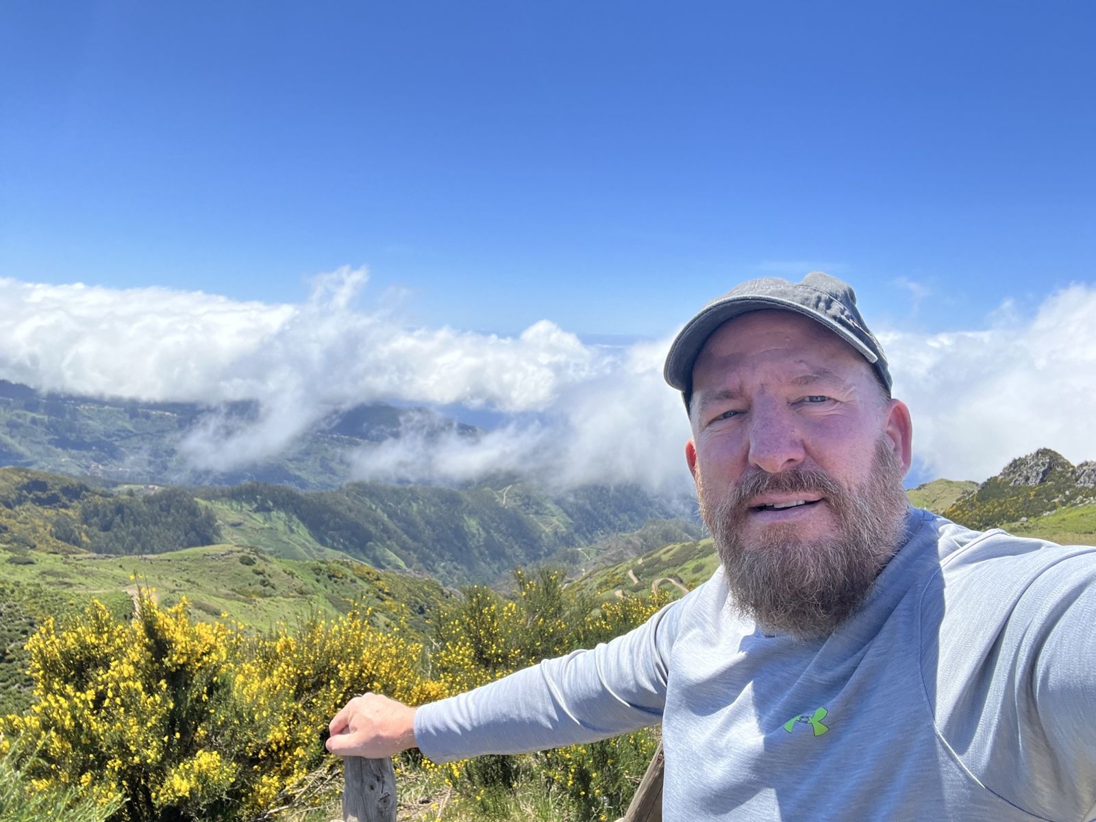 Mike at a high viewpoint in Madeira, green hills and a sea of cloud behind him