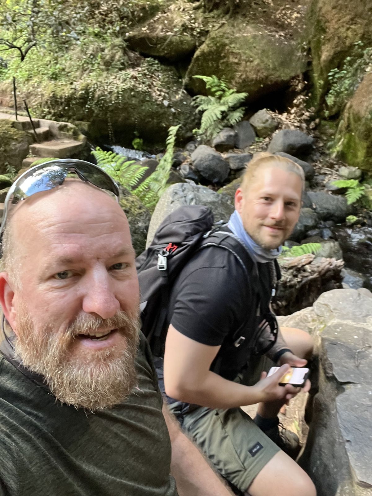 Mike and one of the brothers resting by a forest stream with ferns