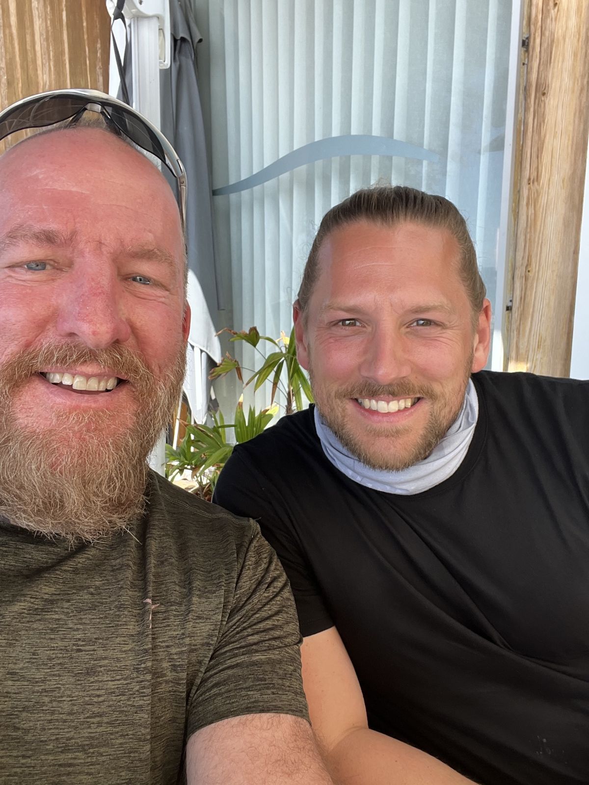 Mike and one of the brothers smiling in a close-up selfie at a cafe