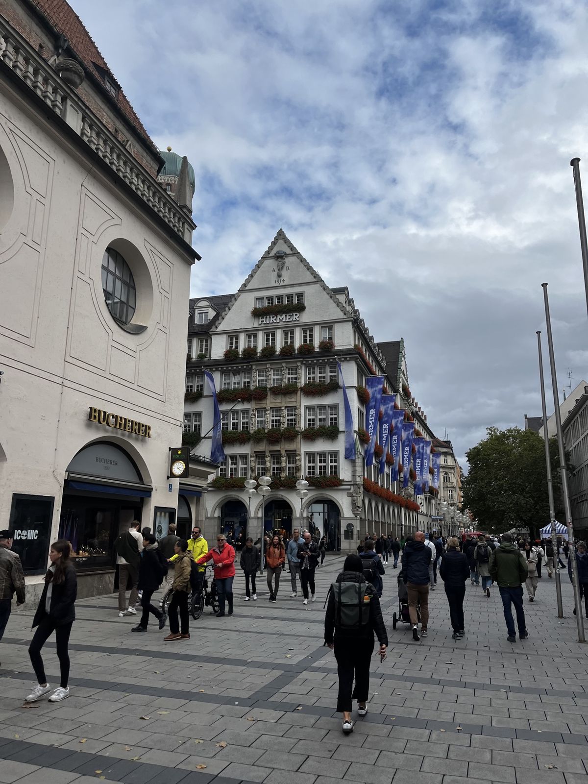 Pedestrians on Munich's Kaufingerstrasse with the Hirmer building and flower boxes