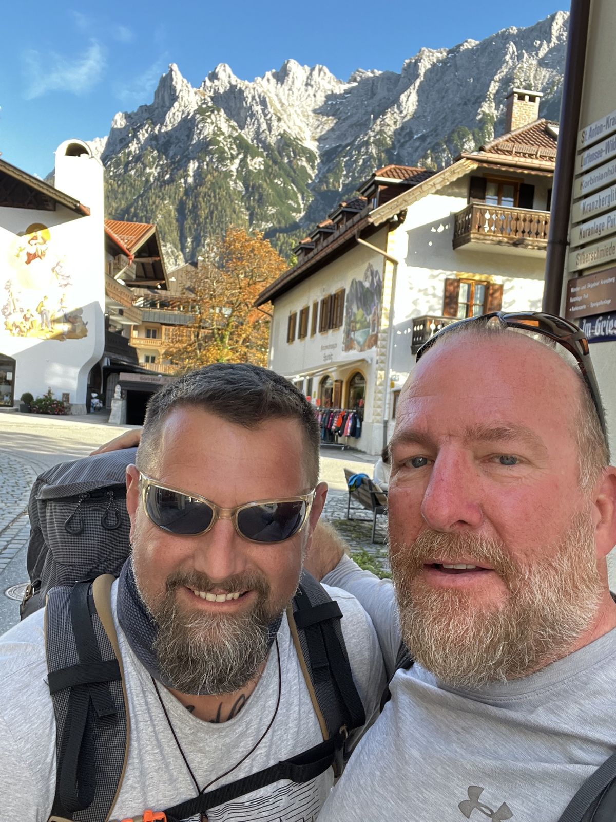 Mike and Nicki selfie in a village with painted houses and a huge rocky mountain behind