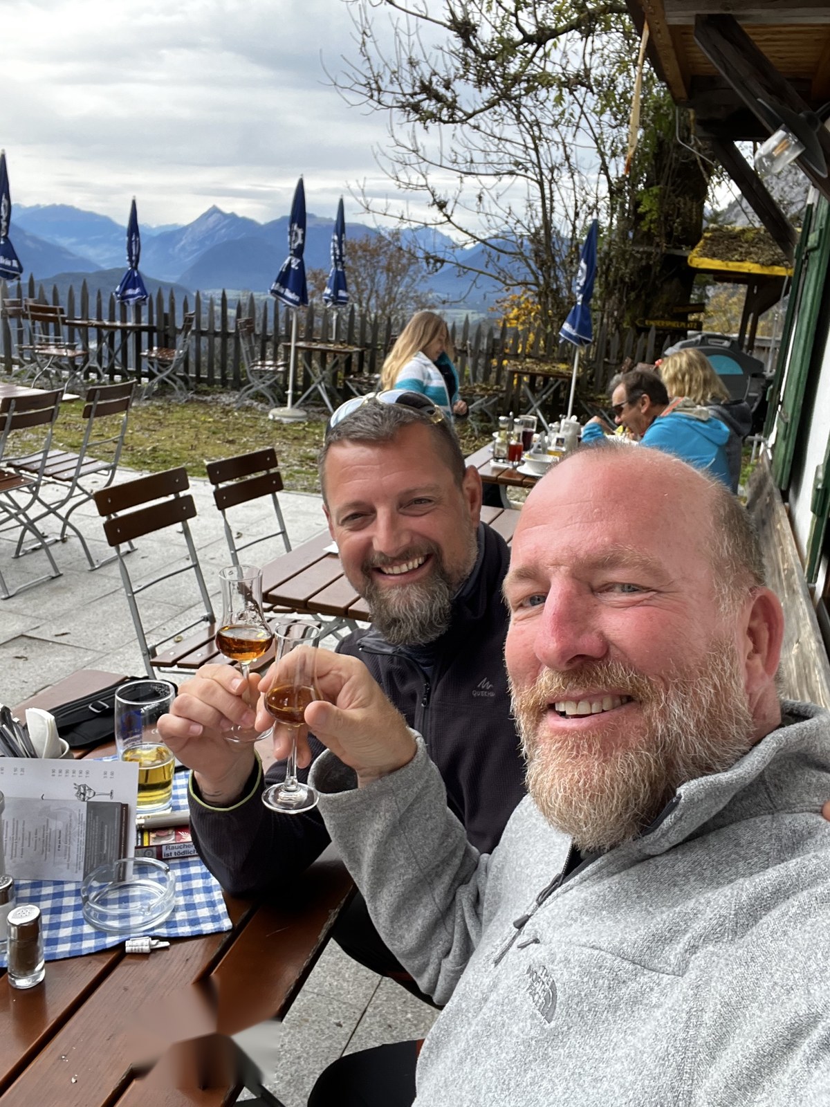 Mike and Nicki raising small glasses on a mountain restaurant terrace