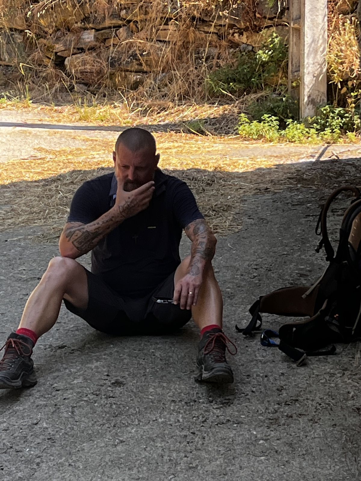 Nicki sitting on the ground beside his pack, resting on the trail