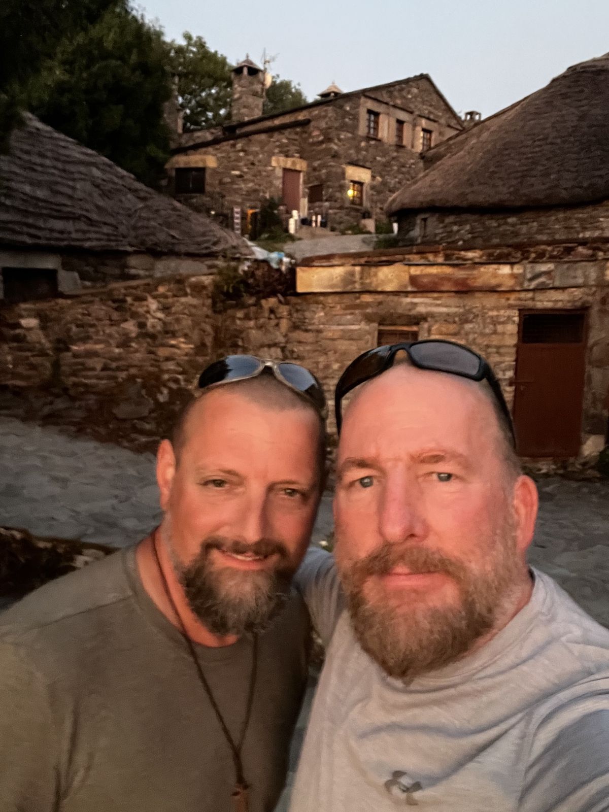 Nicki and Mike selfie at dusk in a stone village with thatched palloza roofs