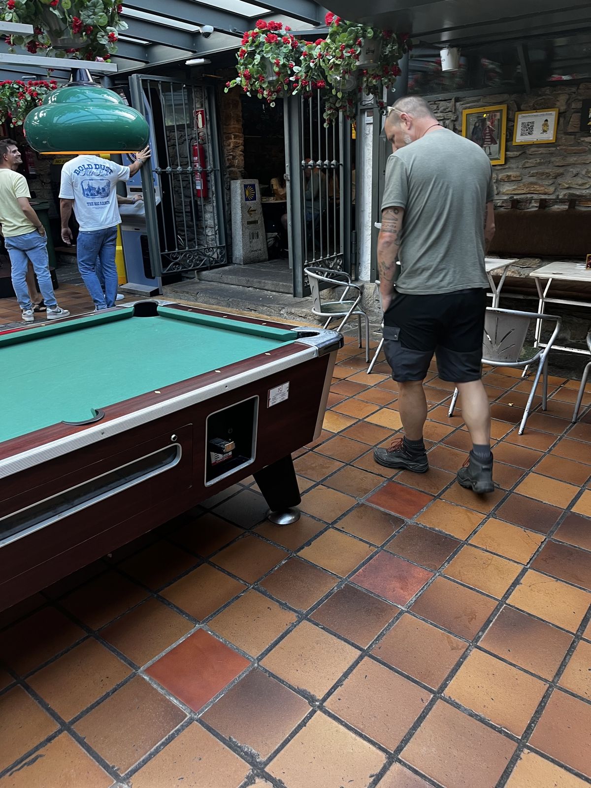Nicki standing beside a pool table in a tiled courtyard bar