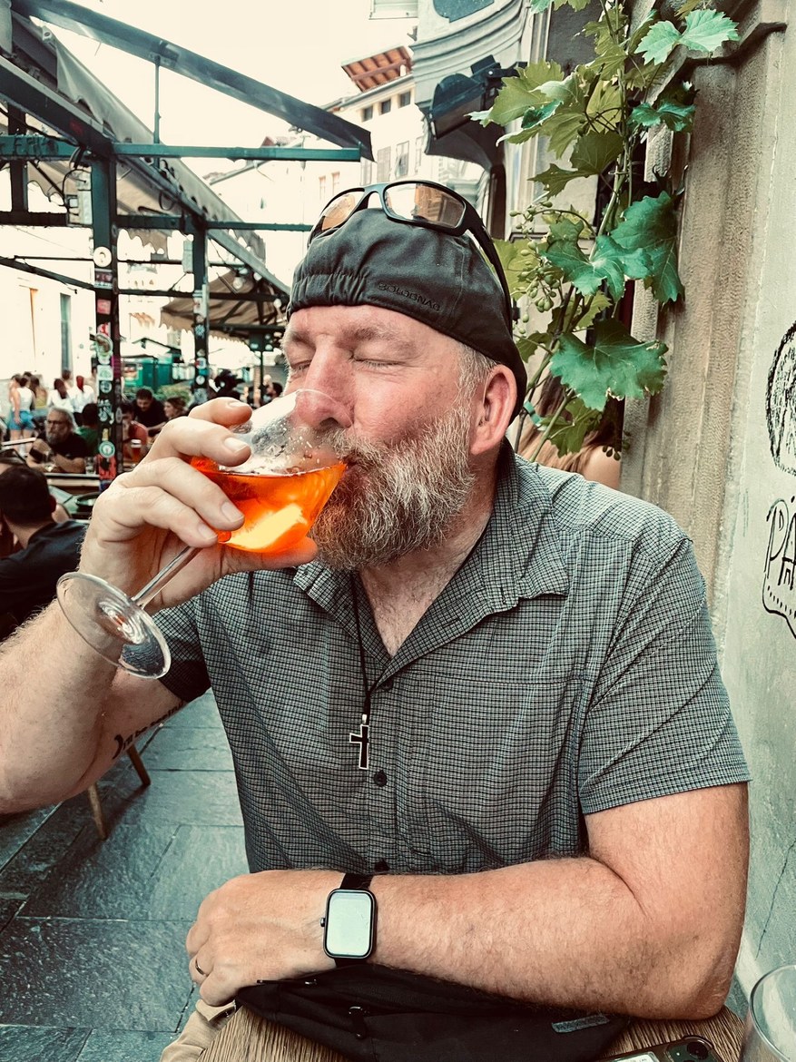 Mike sipping an Aperol spritz at an outdoor café, eyes closed
