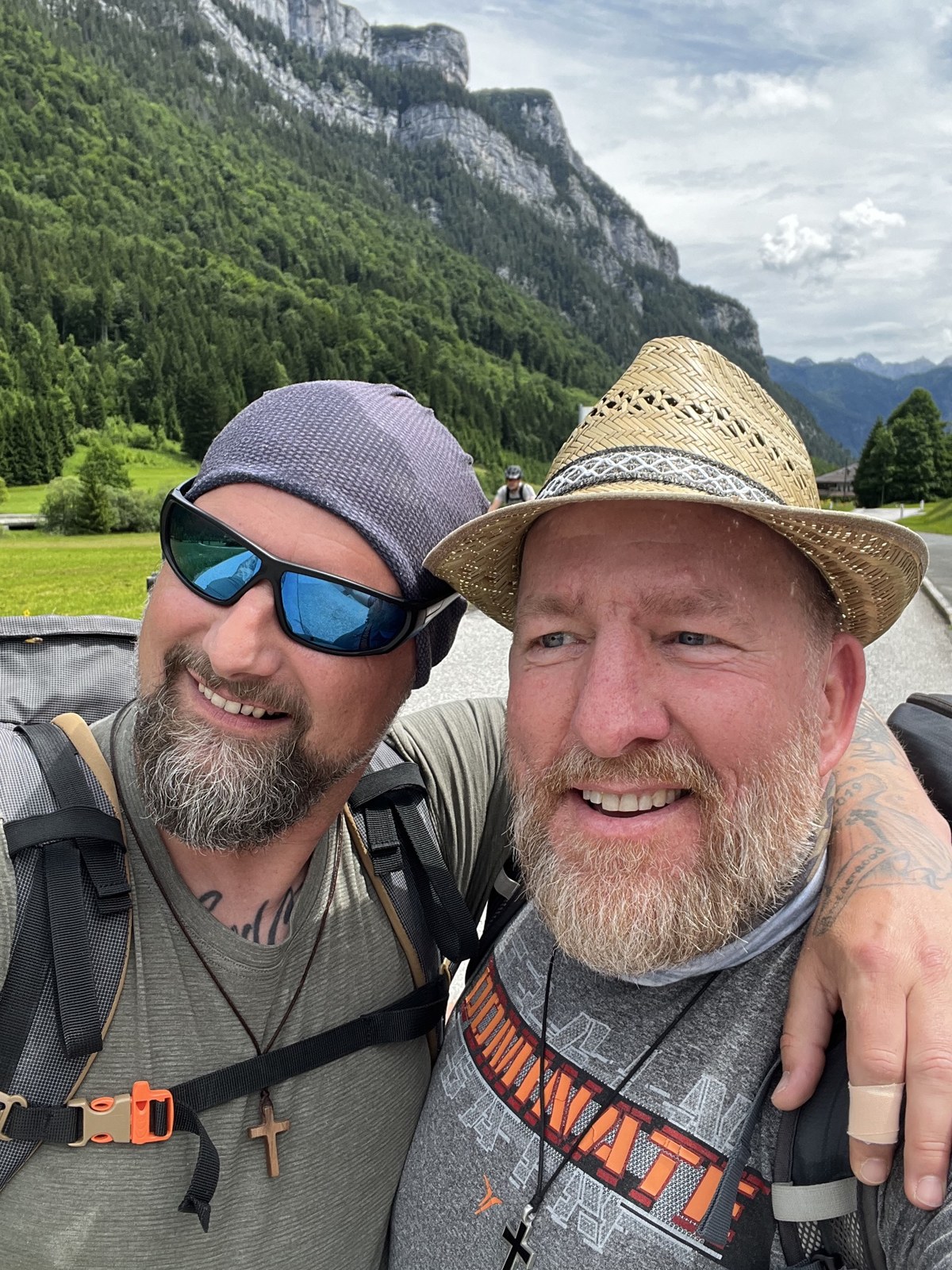 Nicki and Mike taking a selfie on the trail, forested cliffs behind them