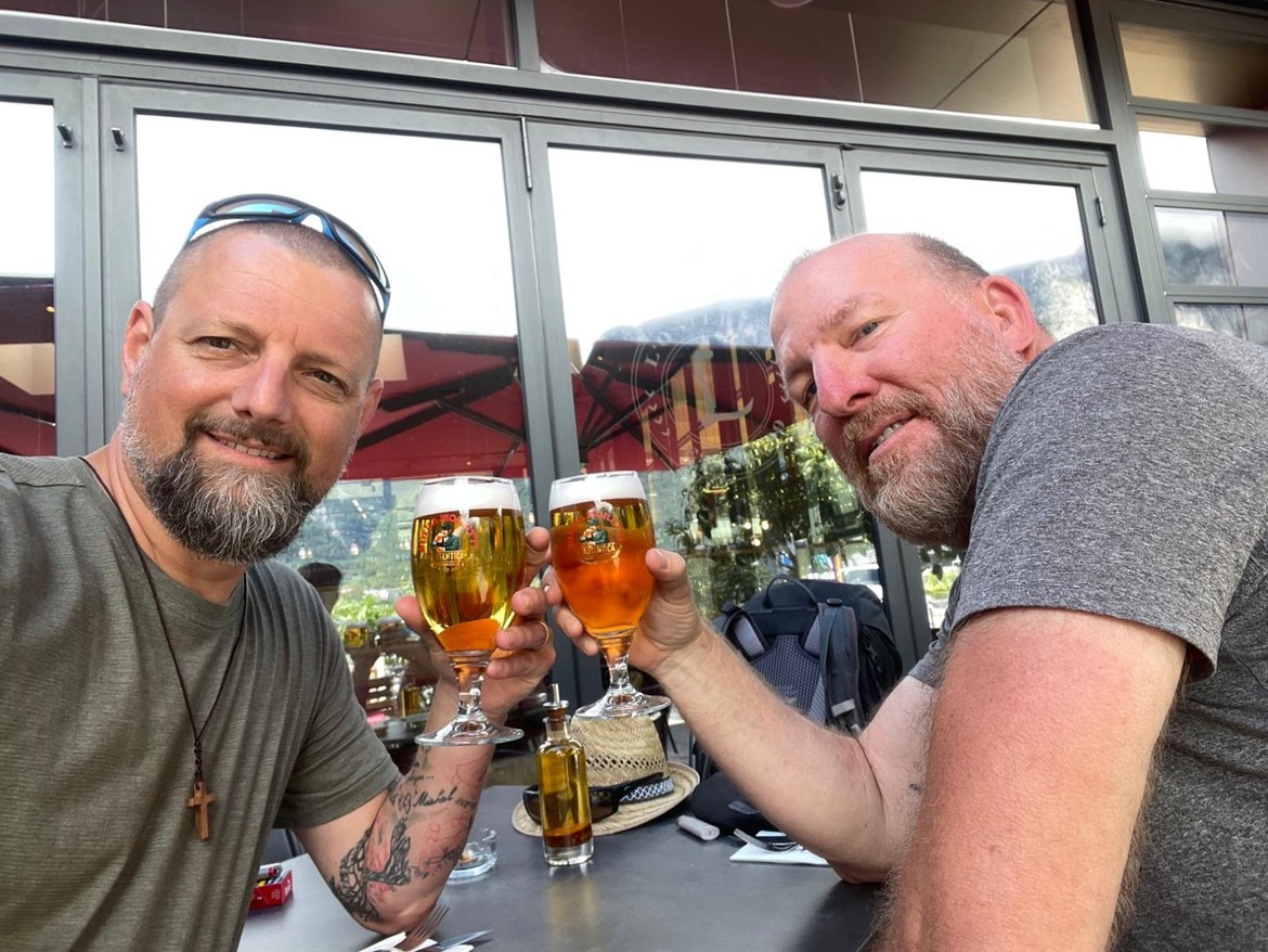 Nicki and Mike clinking beer glasses at an outdoor table