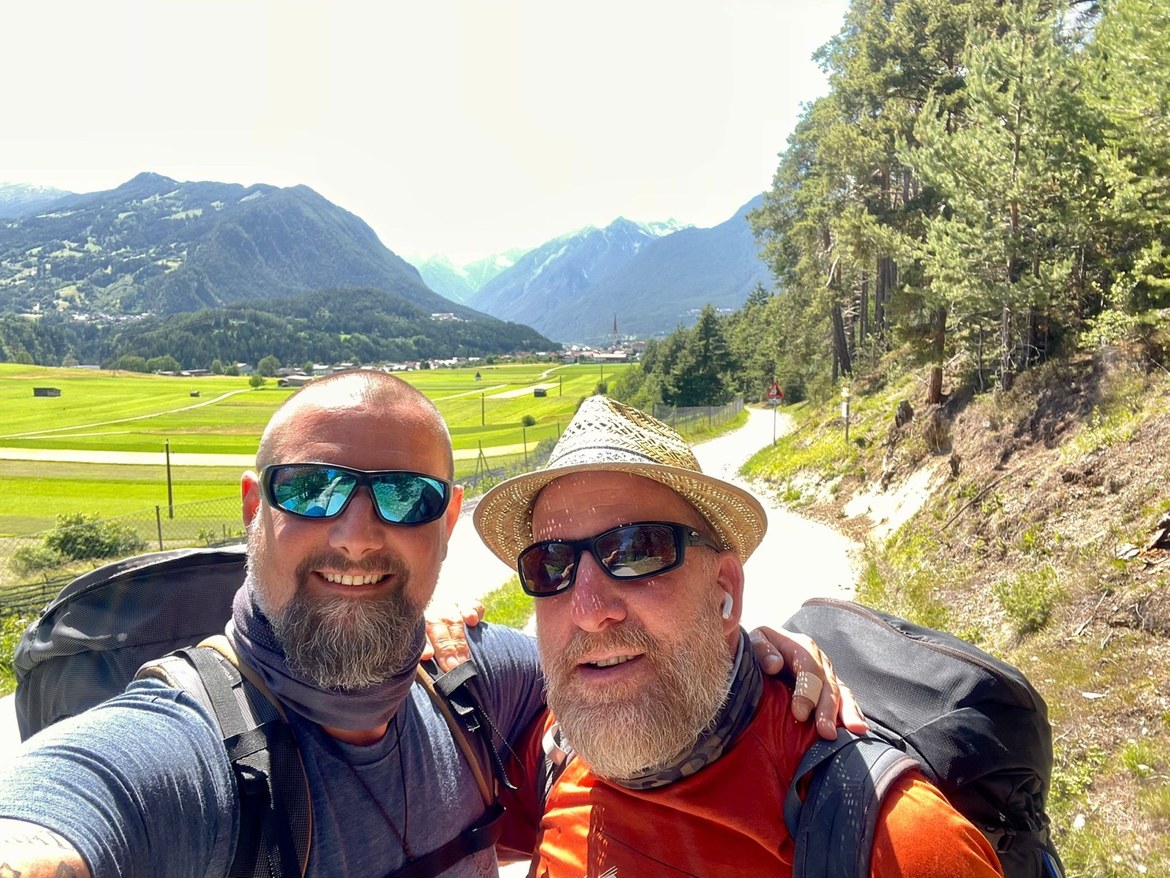 Nicki and Mike taking a selfie with a green valley and peaks behind them