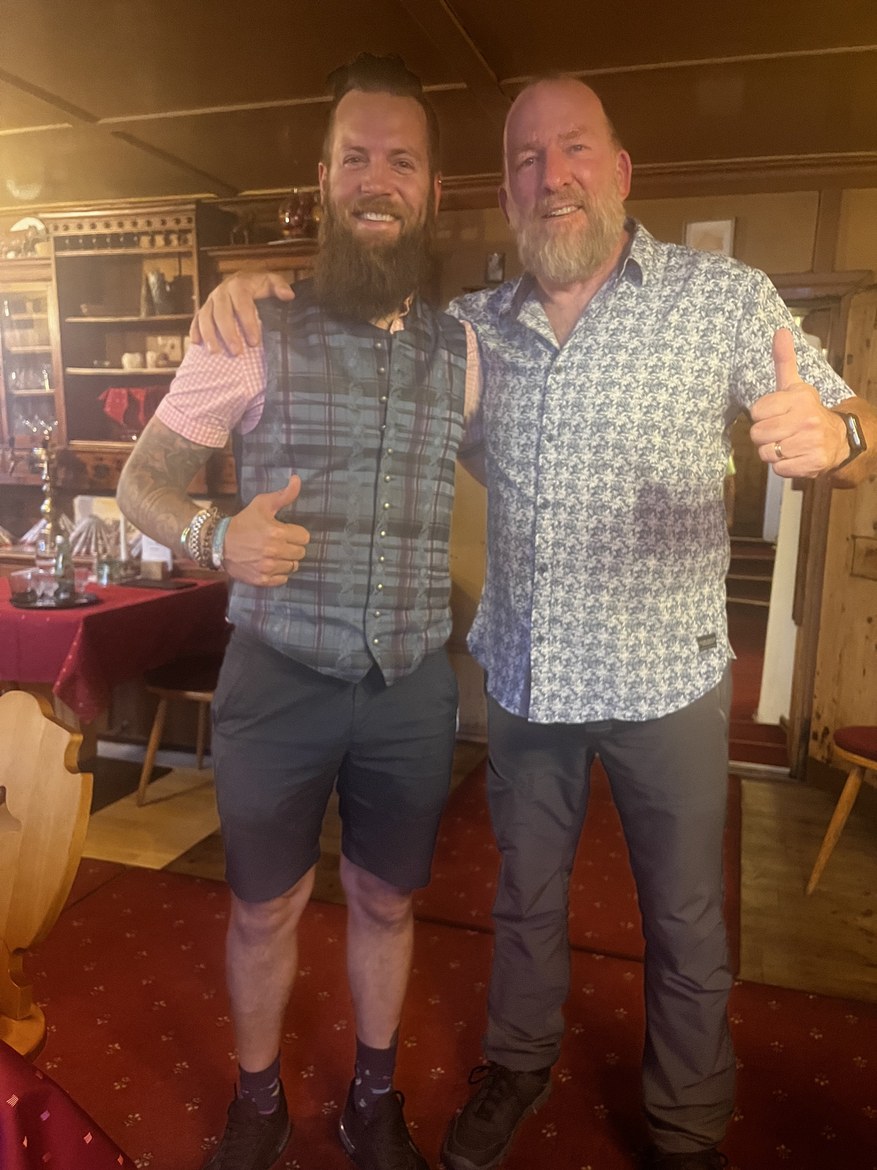 Mike with the waiter in a wood-panelled restaurant, both giving a thumbs up